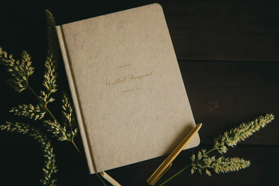 Aufgeschlagenes Hochzeitsplaner-Notizbuch mit Stift und Kalligrafie